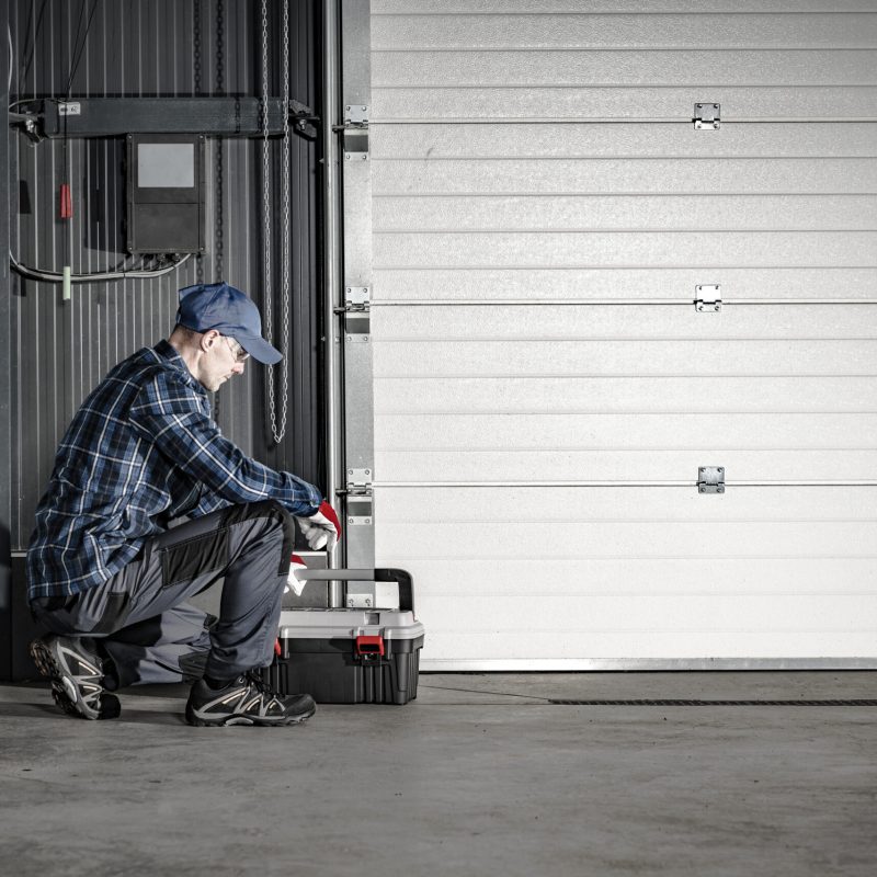 Caucasian Technician in His 40s Servicing Commercial Dock Garage Gate. Industrial Theme.